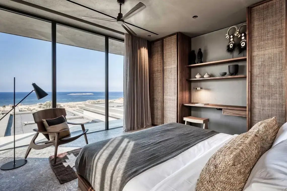 Hotelzimmer mit großem Bett und bodentiefen Fenstern mit freiem Blick auf das Meer.
