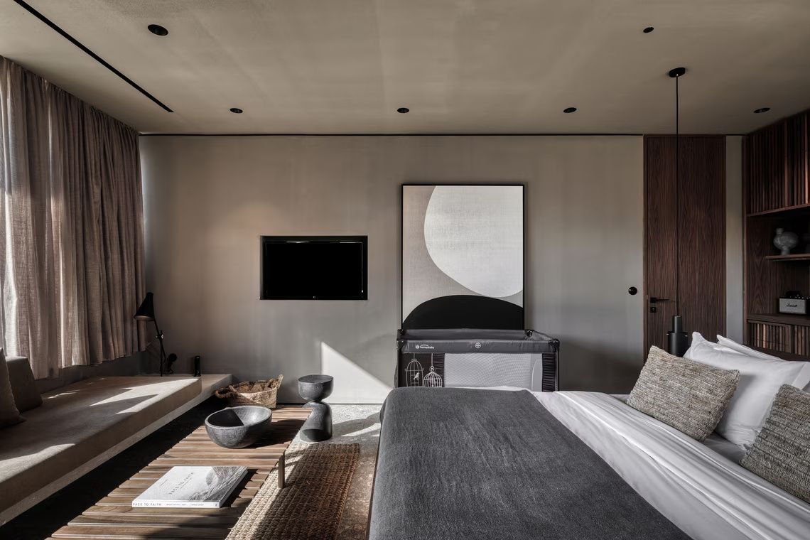 Moderner Schlafbereich mit großem Doppelbett, Fernseher an der Wand und Kunstwerk.