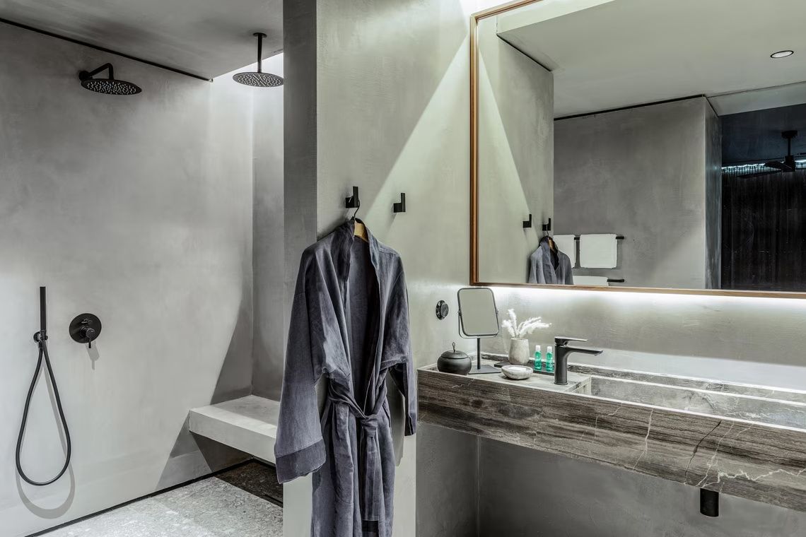Badezimmer mit grauem Waschtisch, großem Wandspiegel und hängendem Bademantel