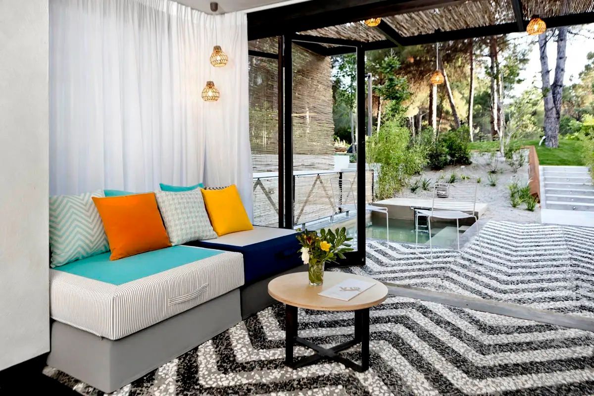 Sitzecke mit bunten Kissen und Couchtisch vor offenem Durchgang zum privaten Pool.