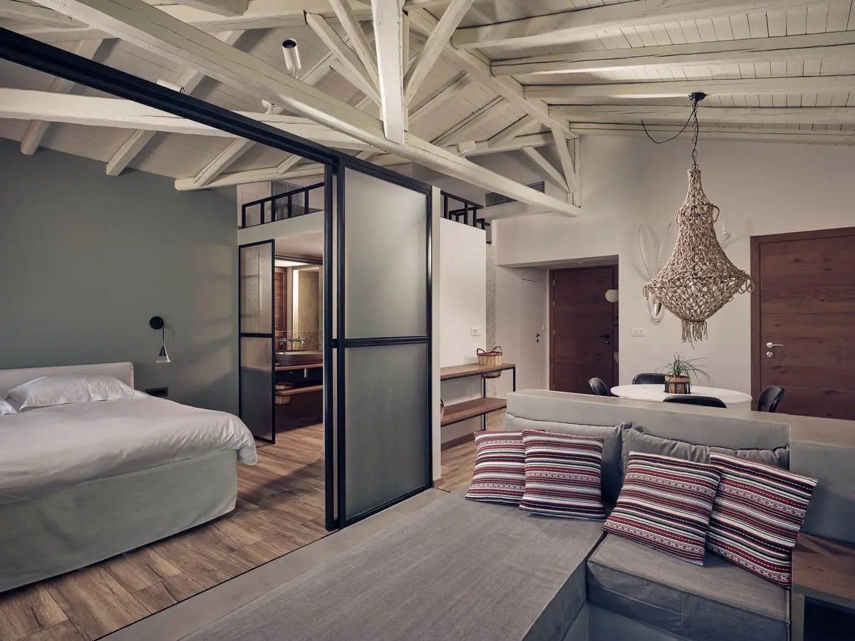 Geräumige Suite mit Schiebetür aus Glas, Holzbalken an der Decke und Sitzbereich.