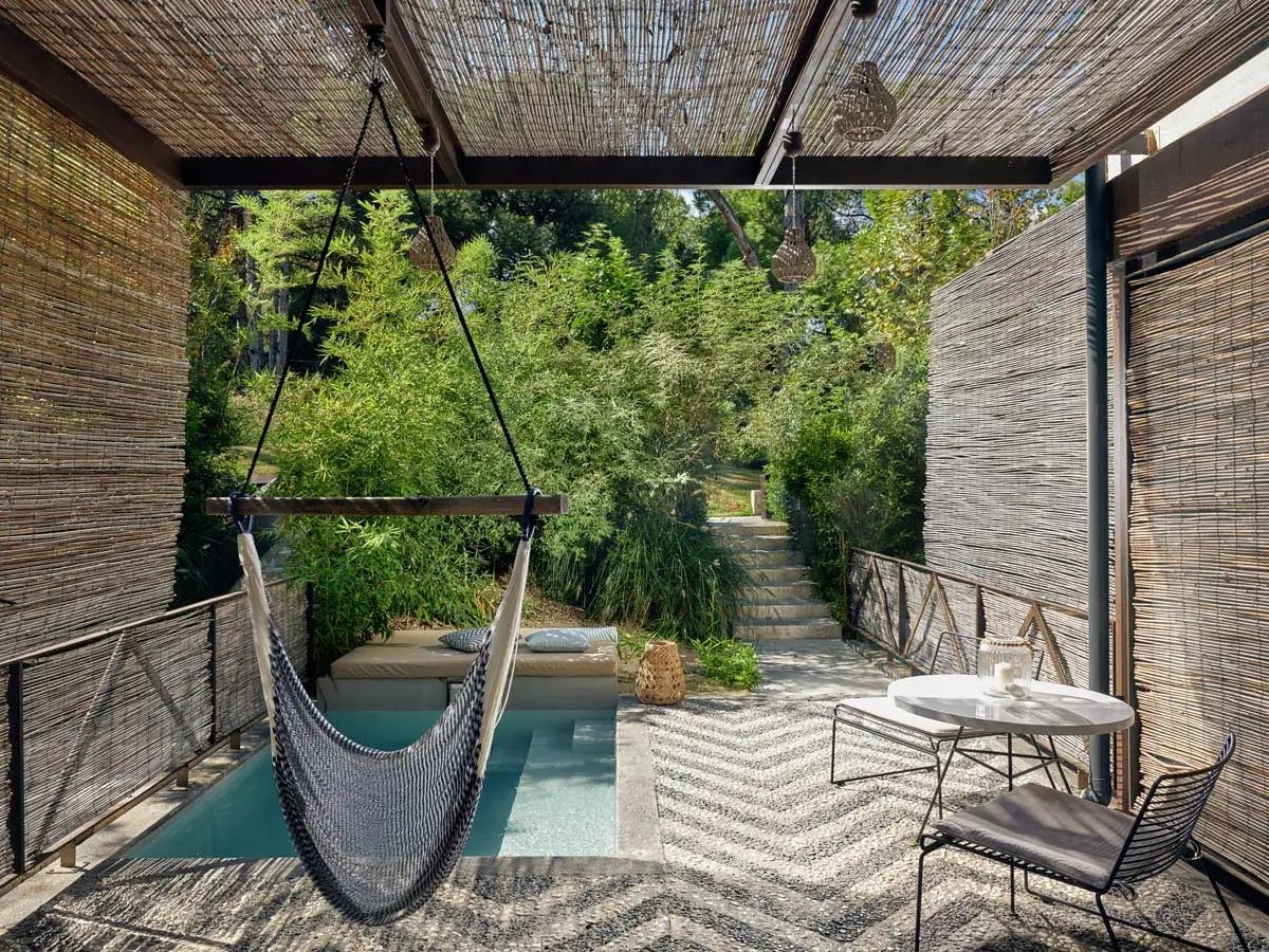 Überdachte Terrasse mit Hängesessel, Sitzbereich und einem kleinen Pool im Garten.