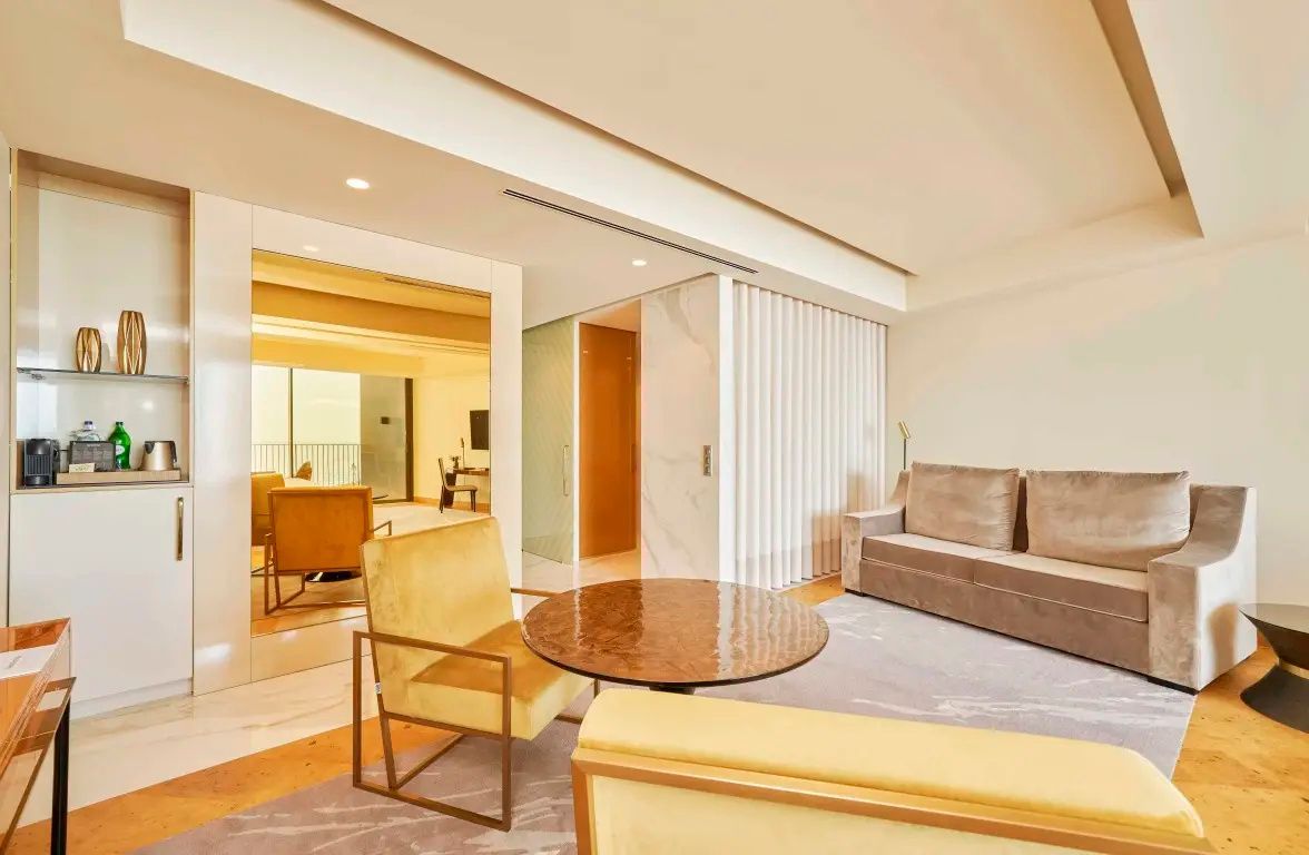 Sitzbereich im Zimmer mit beige-braunem Sofa, gelbem Polstersessel und rundem Beistelltisch.