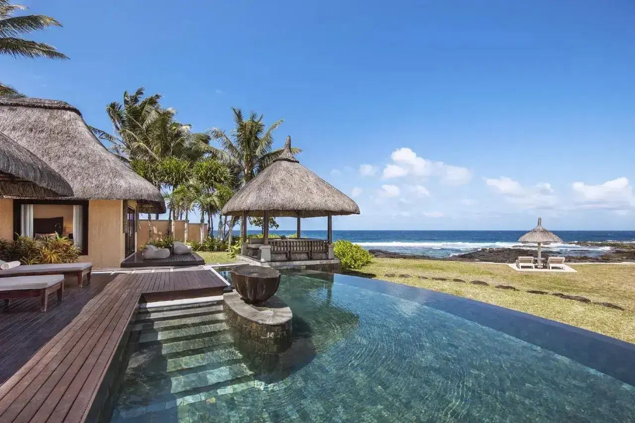 Privater Pool auf der Holzterrasse mit Pavillon mit Reetdach und Blick auf das nahe Meer.