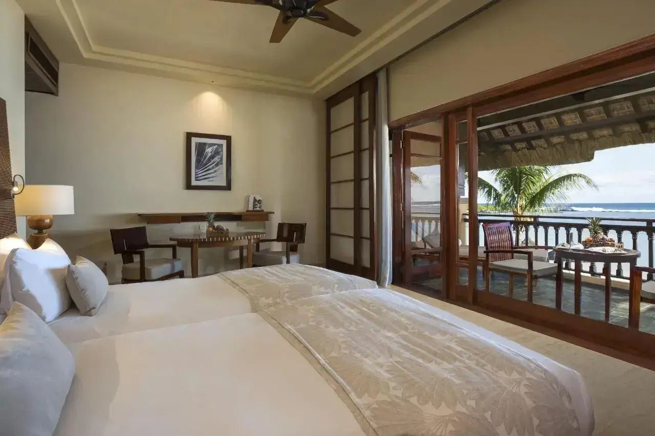 Modernes Schlafzimmer im Hotel mit zwei Betten, Sitzbereich und Zugang zum Balkon.