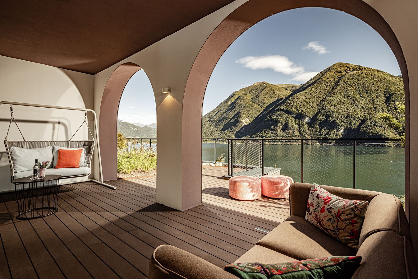 Überdachte Terrasse mit Rundbögen, Sitzmöbeln und Panoramablick auf den See und die Berge.