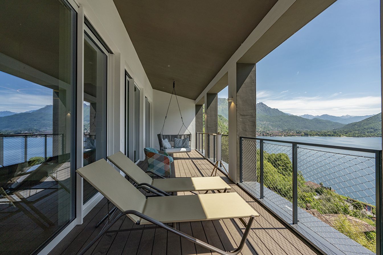 Überdachte Terrasse mit zwei Sonnenliegen und Panoramablick auf den See.