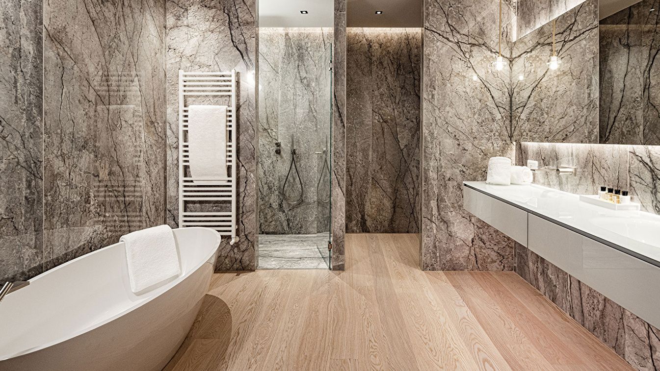 Badezimmer mit marmorierten Fliesen, freistehender Badewanne und bodengleicher Dusche.