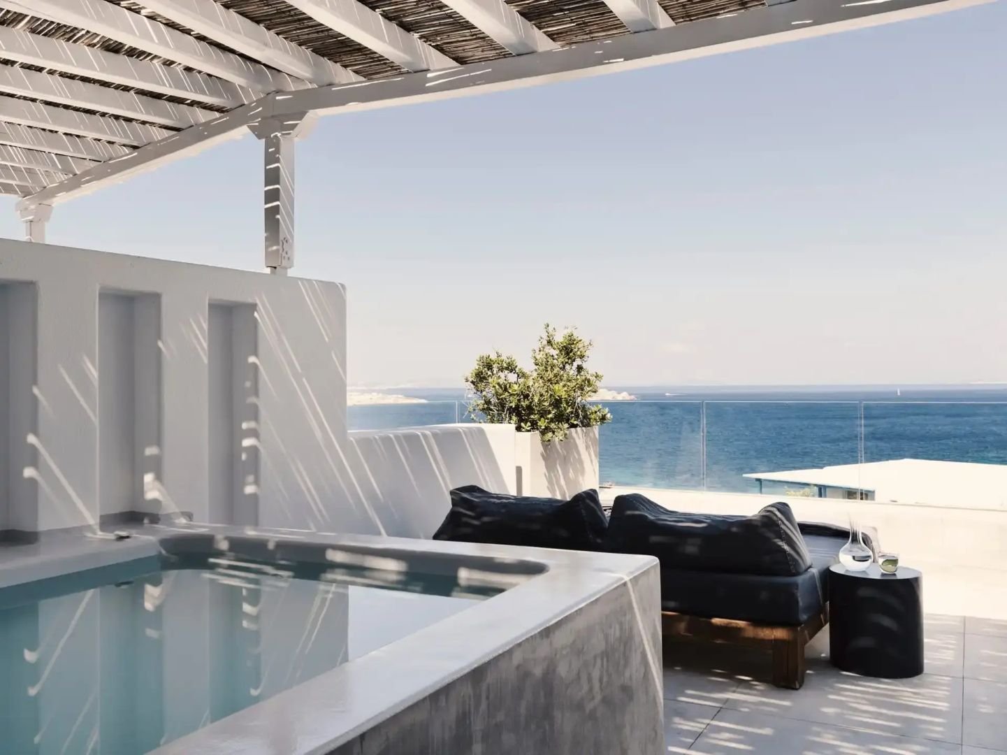 Überdachte Terrasse mit Whirlpool und Sitzgelegenheiten sowie direktem Blick auf das Meer.