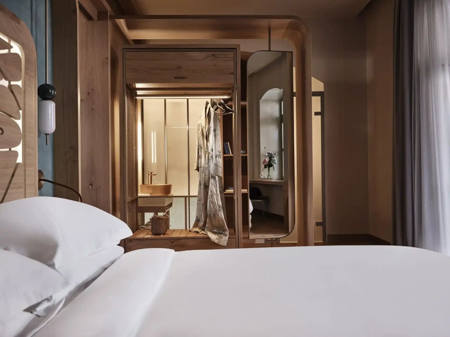 Bett mit weißer Bettwäsche und Holzkleiderschrank mit Spiegel im Raum.