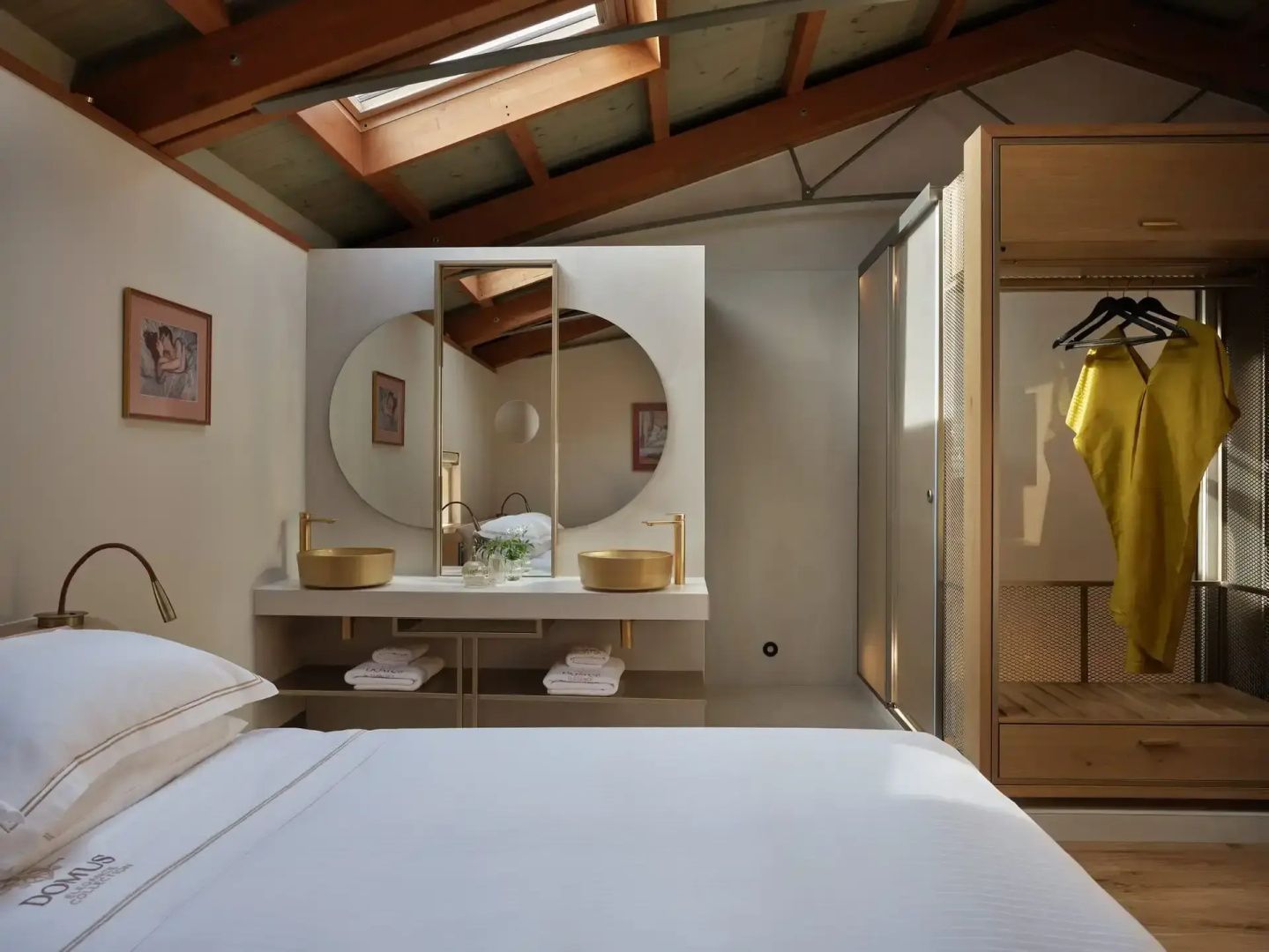 Hotelzimmer mit Doppelbett und offen integriertem Waschtisch unter Dachschräge.