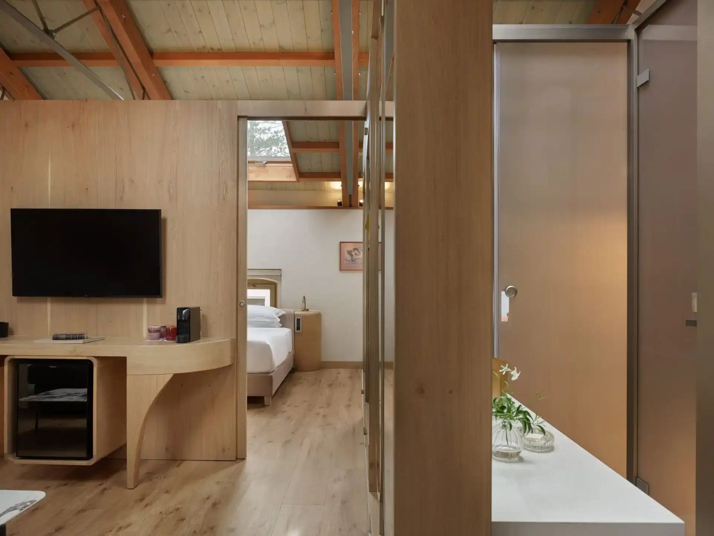 Innenansicht eines Zimmers mit Fernseher, Holzverkleidung und Blick zum Bett.