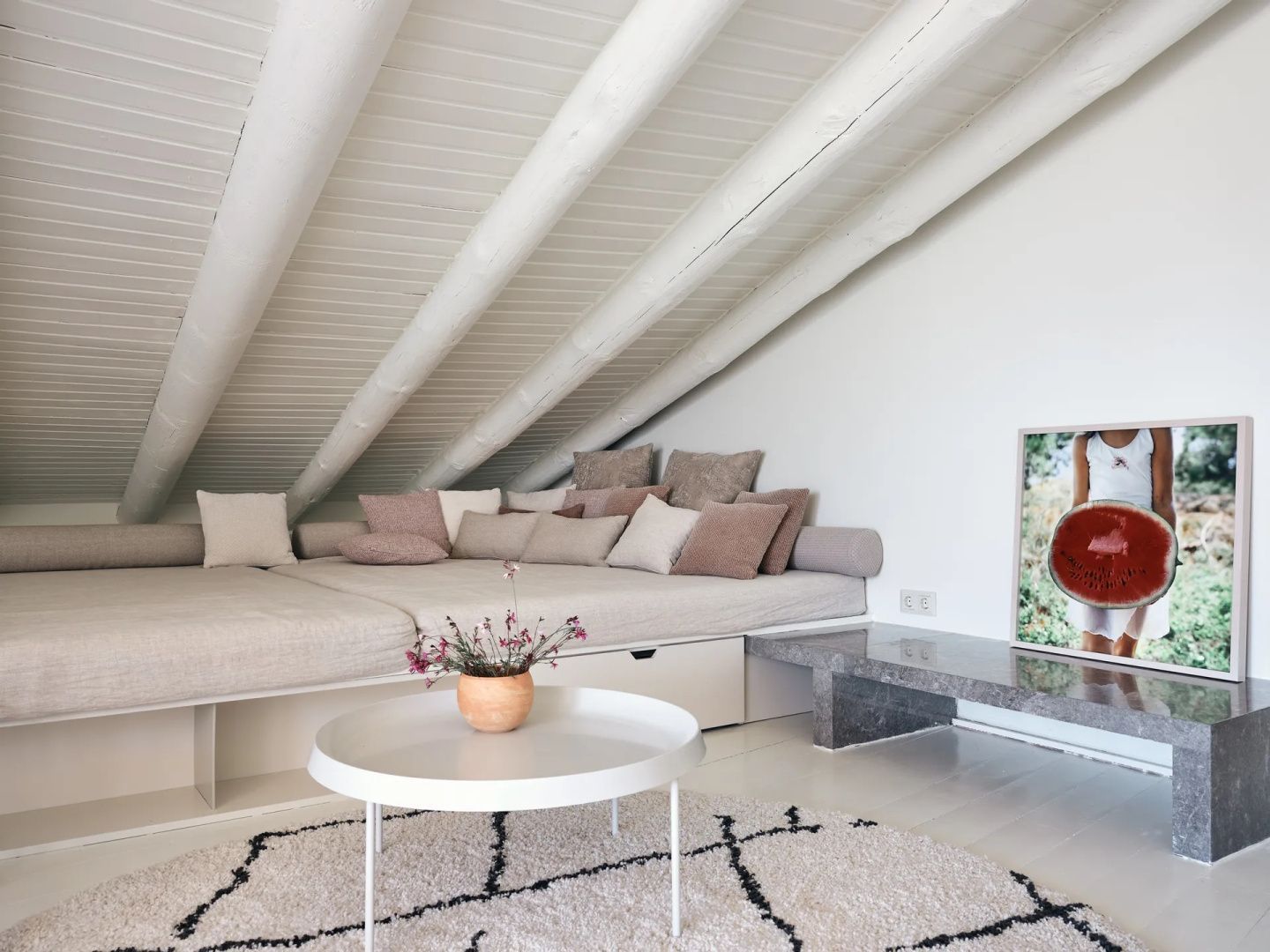 Große Sitzecke unter einer Holzdecke mit flachem Bett, Kissen und Couchtisch.