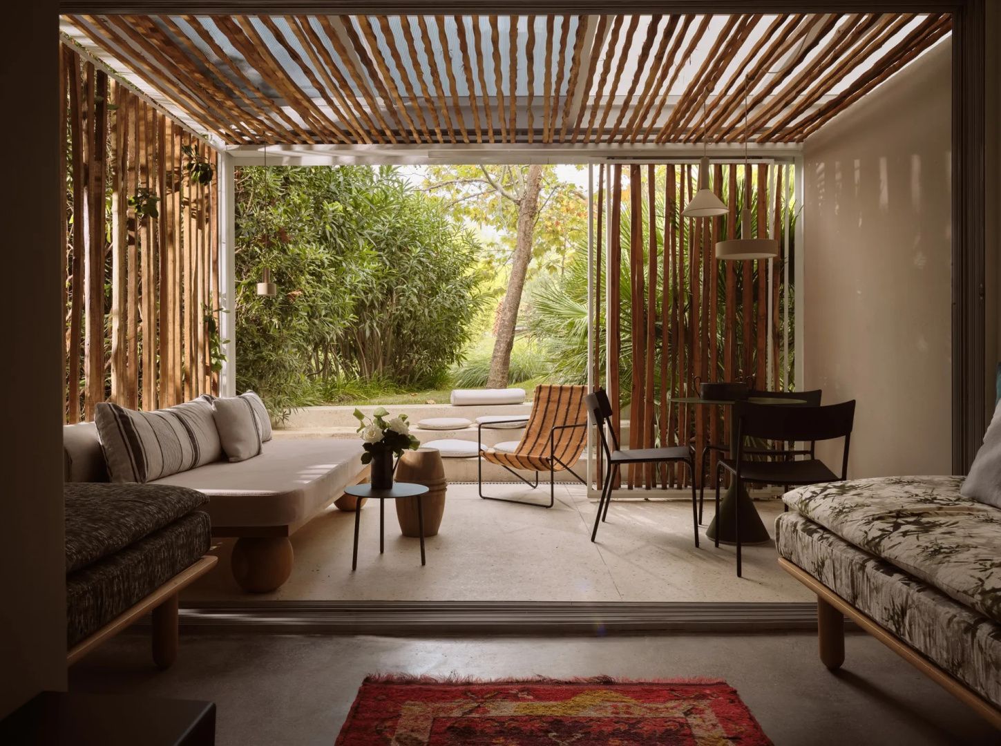 Wohnbereich einer Suite mit Holzdecke, gemütlichen Sitzmöbeln und Blick in den grünen Garten.