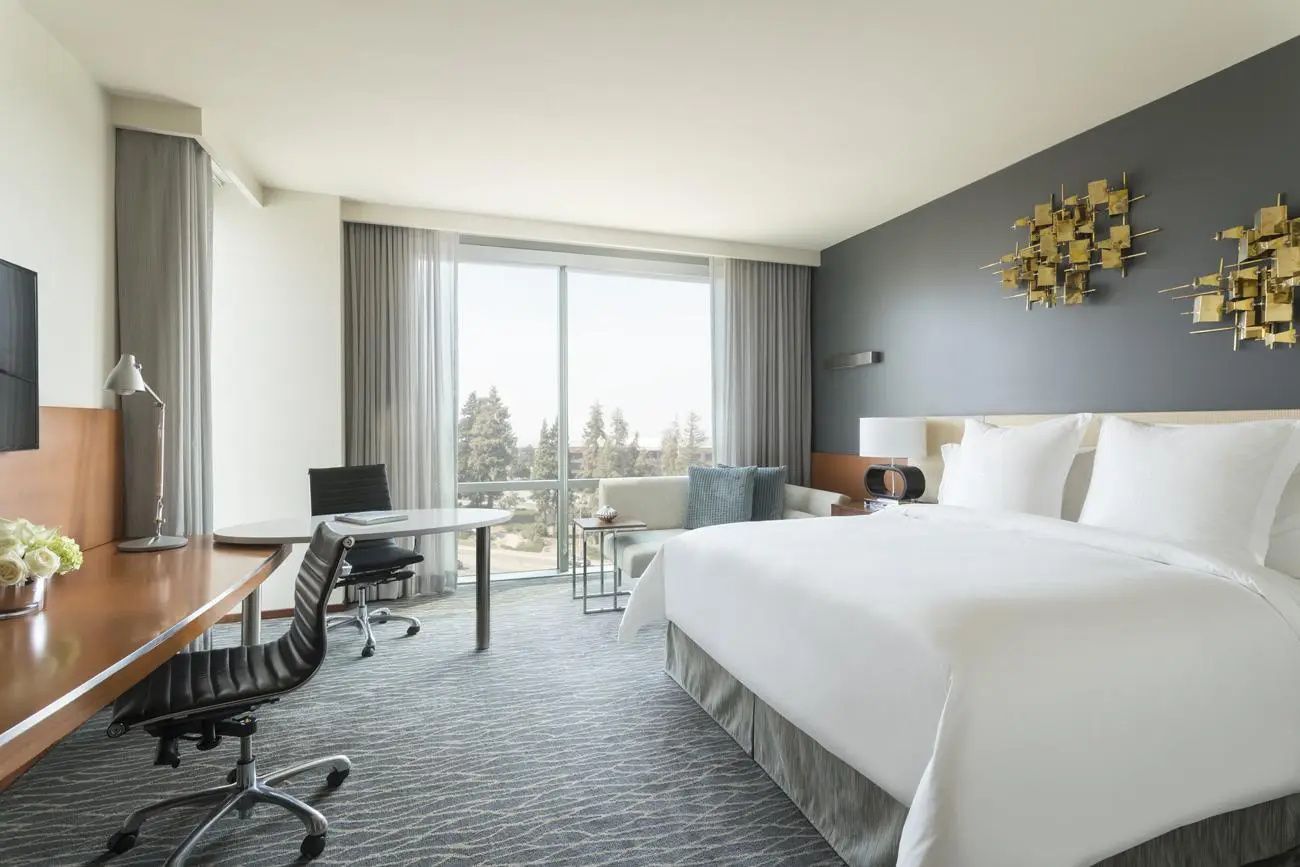 Helles Hotelzimmer mit Doppelbett, Sitzbereich und Sicht nach draußen.