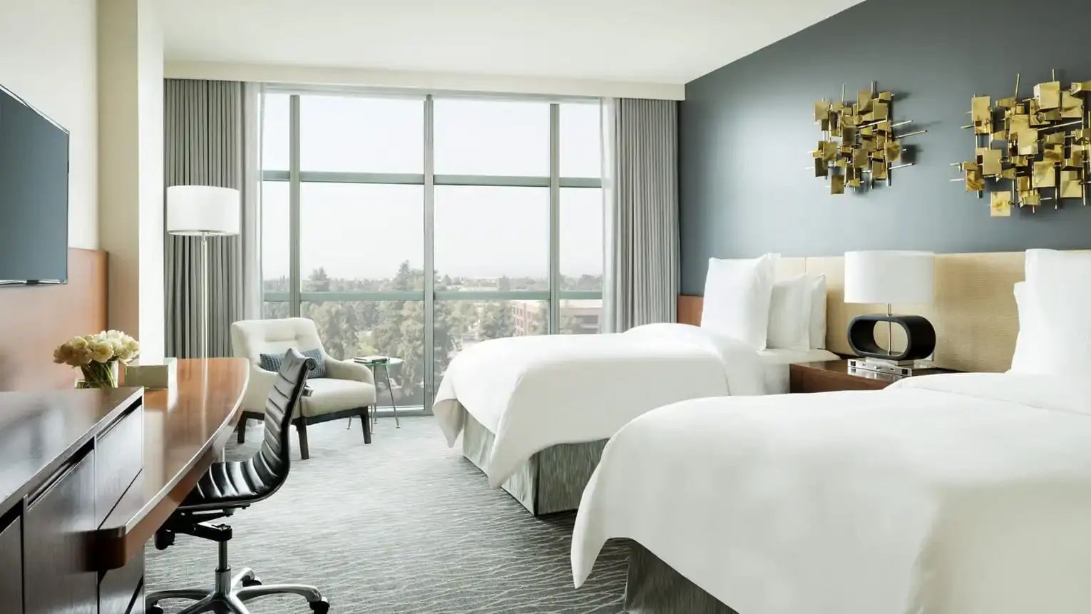 Modern eingerichtetes Gästezimmer mit zwei Einzelbetten und Sessel.