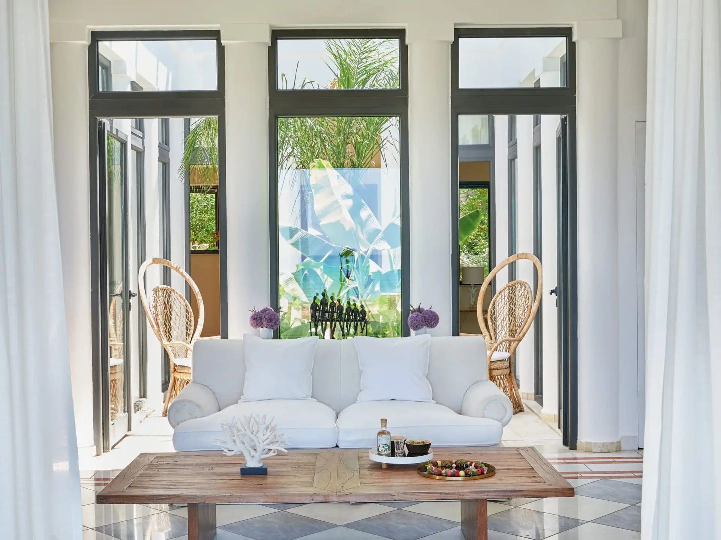Heller Wohnbereich mit weißem Sofa, Holztisch und großen Fensterfronten