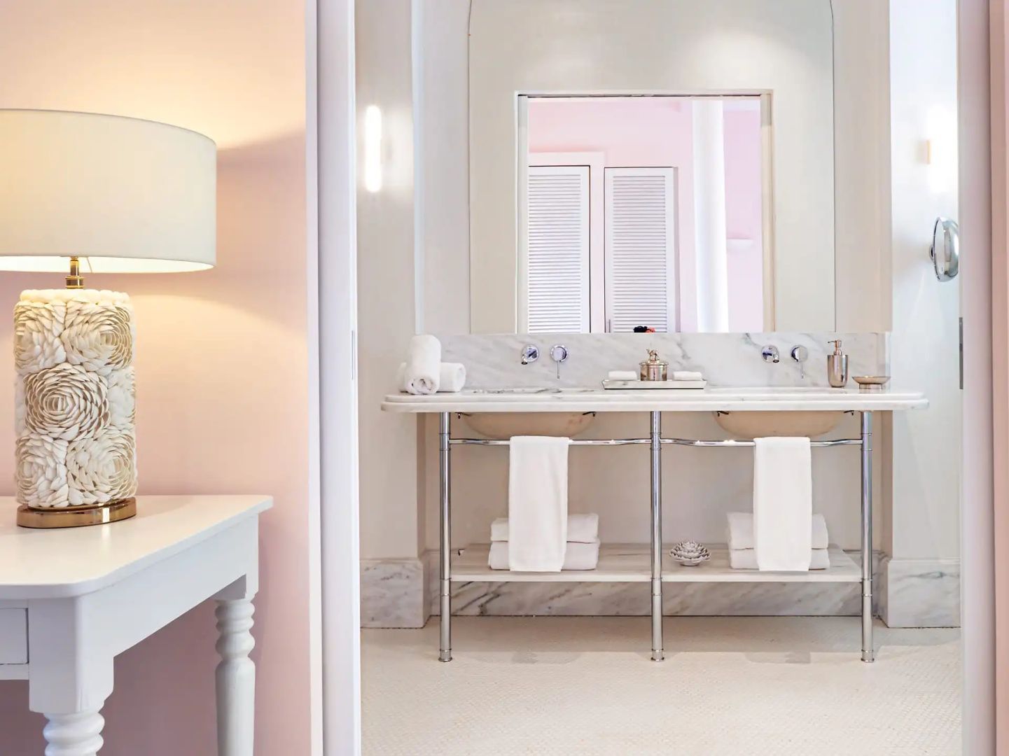 Badezimmer mit Doppelwaschtisch aus Marmor, großen Spiegeln und weißen Handtüchern.