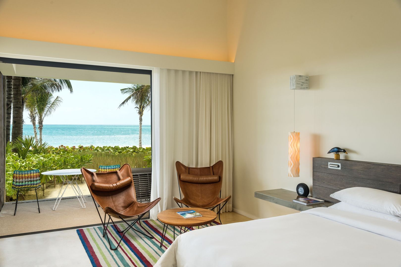 Sitzbereich im Hotelzimmer mit zwei Ledersesseln und Blick durch die Glastür auf das Meer.