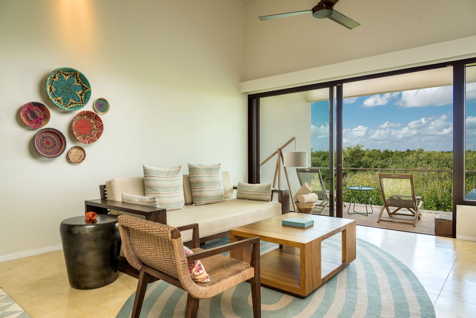 Wohnbereich einer Suite mit hellem Sofa, Holzcouchtisch und Balkon mit Blick in die Natur.