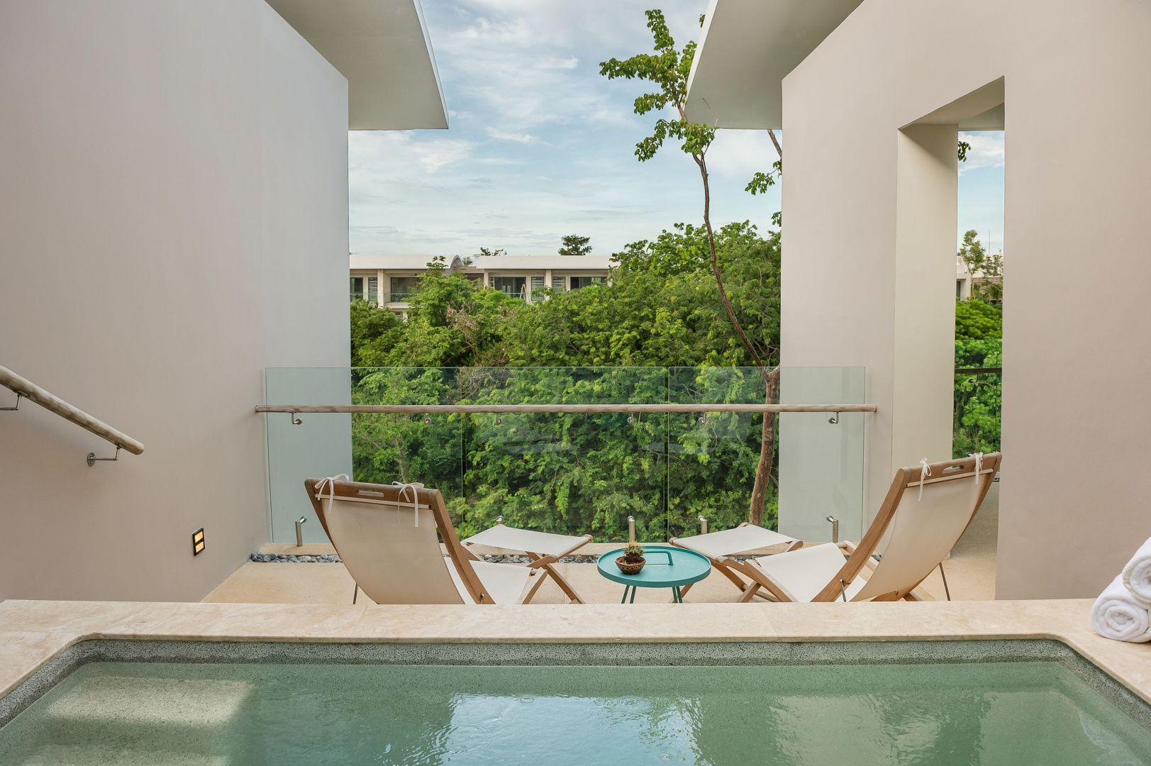 Private Terrasse mit kleinem Pool, zwei Liegestühlen und Blick auf grüne Natur.