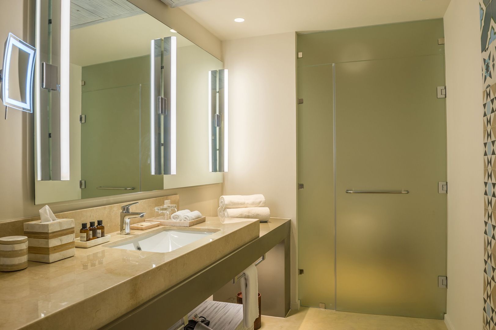 Modernes Badezimmer mit breitem Waschtisch, großem Spiegel und Glastür zur Dusche.