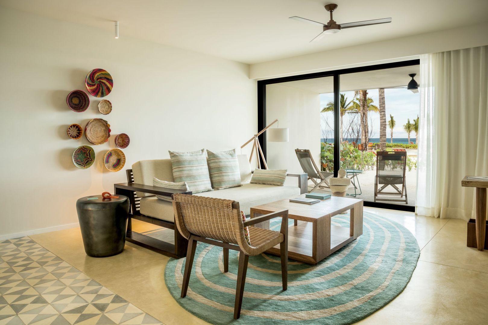 Wohnbereich einer Suite mit Sofa, Holzsessel und Blick durch die Terrassentür ins Freie.