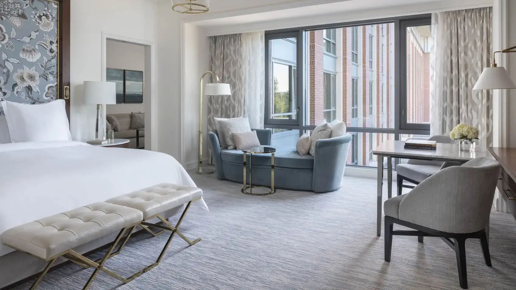 Heller Hotelraum mit modernem Chaiselongue am großen Fenster, Bettbank und neutralen Farben.