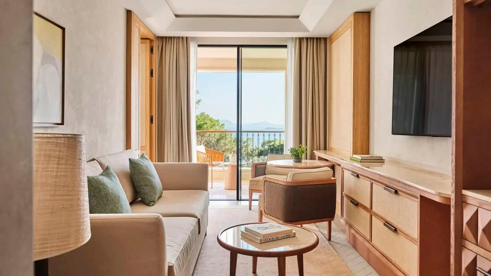 Heller Wohnbereich mit beigefarbenem Sofa und Balkon mit Blick auf das Meer.
