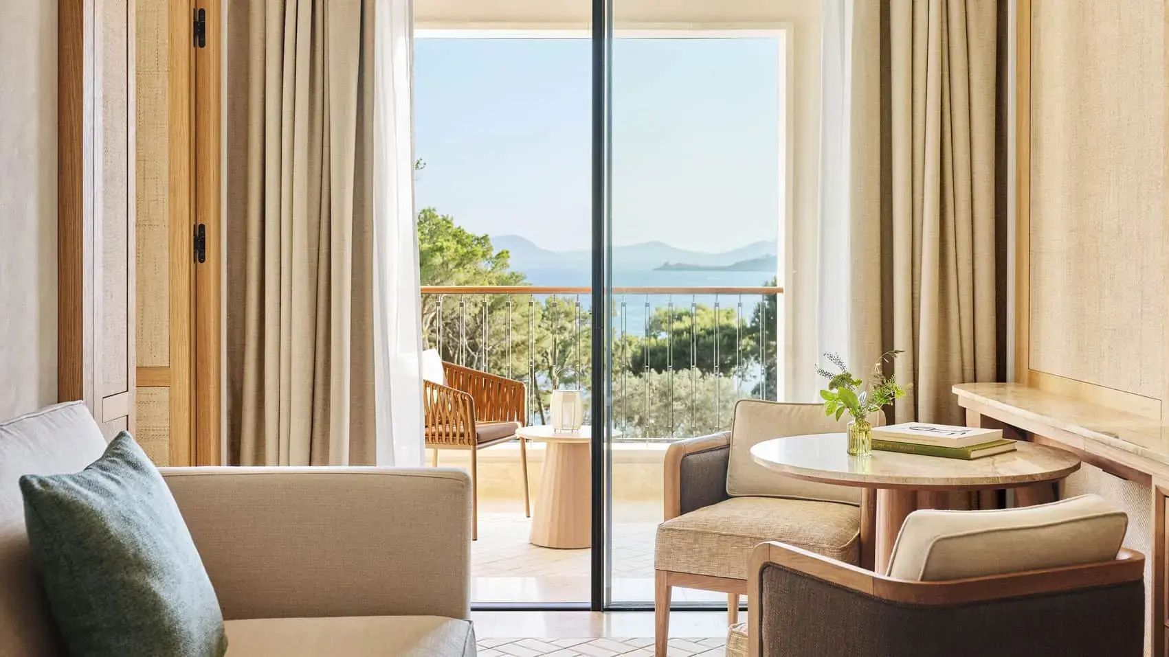 Aussicht vom Innenbereich mit Sitzgelegenheiten auf den Balkon und das Meer.