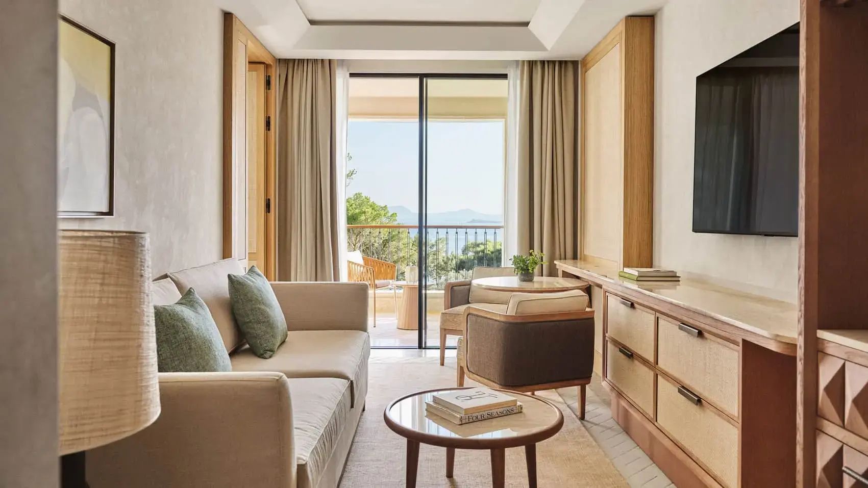 Wohnbereich einer Suite mit Sofa, Sessel und Blick auf den Balkon mit Meersicht.