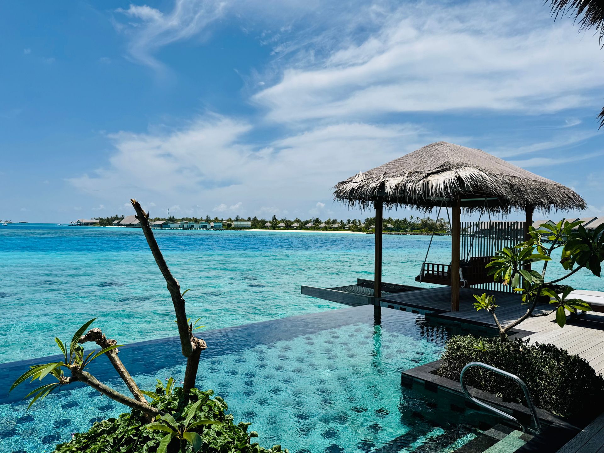 Luxuriöser Bungalow neben Infinity-Pool mit Blick auf türkisfarbenes Wasser