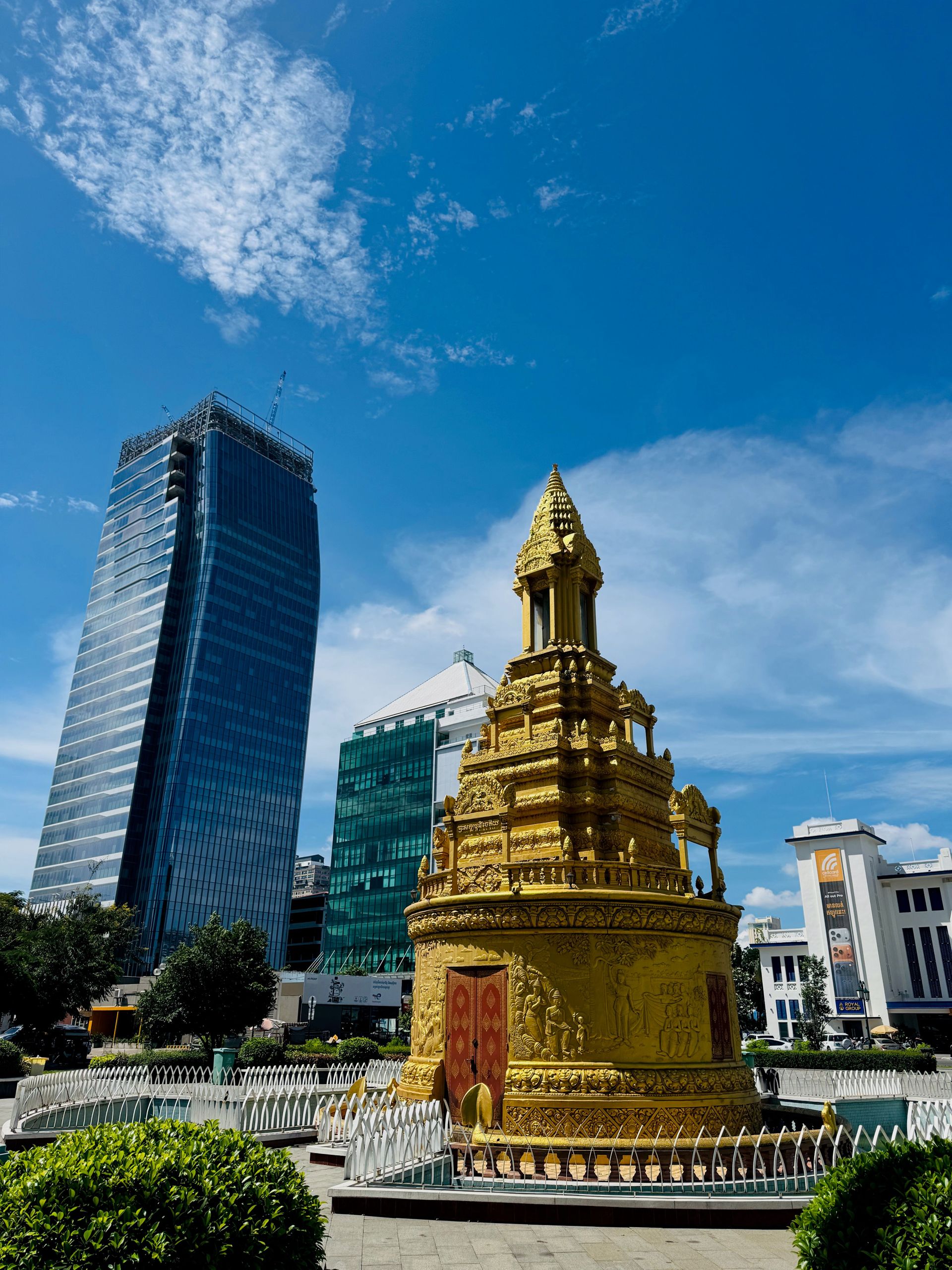 Goldene Stupa vor modernen Hochhäusern mit blauem Himmel im Hintergrund.
