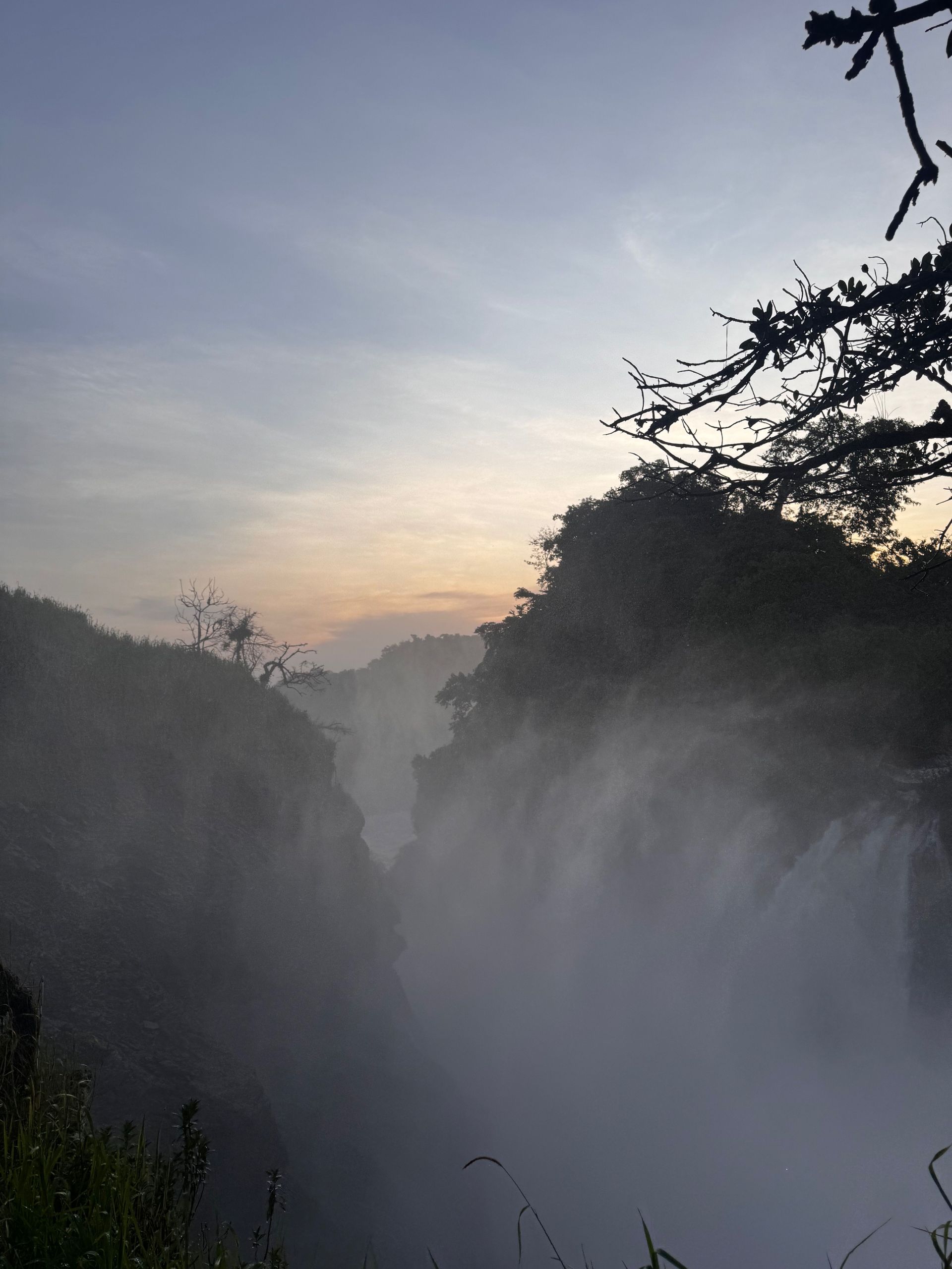 Wasserfall im Nebel bei Sonnenaufgang mit Silhouette von Bäumen