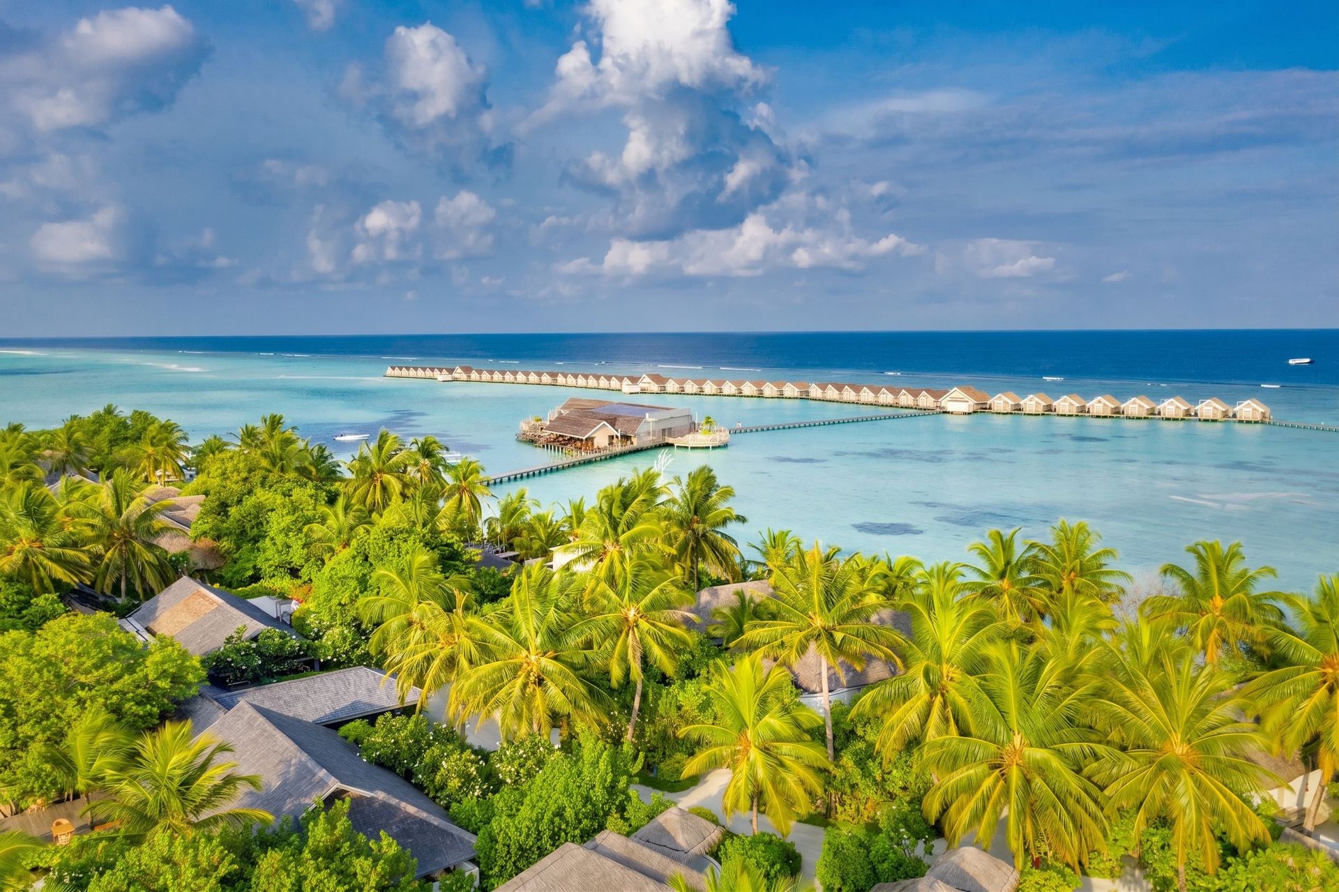 Luftaufnahme eines exklusiven Resorts mit Wasserbungalows im türkisfarbenen Meer