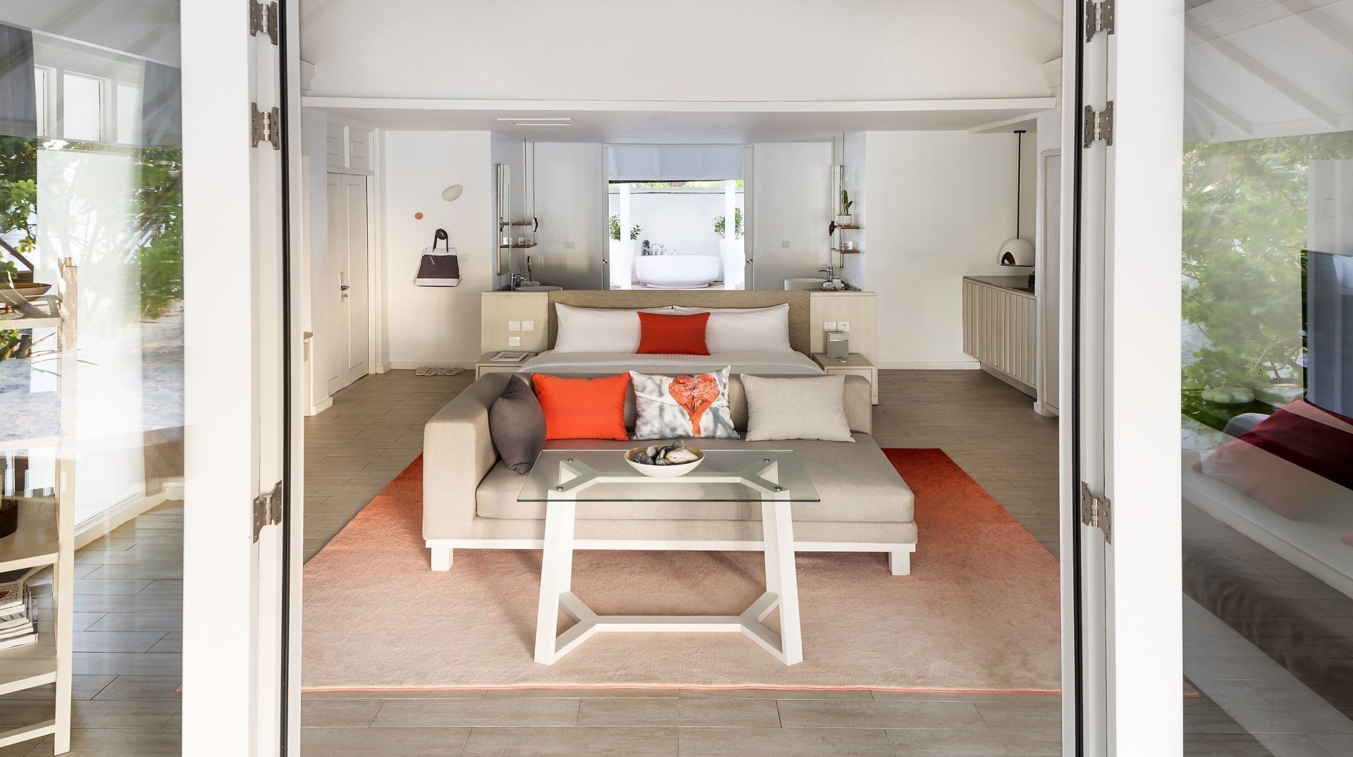 Wohn- und Schlafbereich einer Villa mit Sofa, Glasstisch und Doppelbett.
