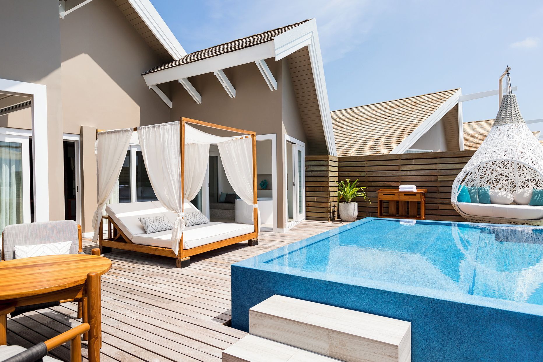 Luxuriöse Terrasse mit Pool, Sonnenbett und modernem Outdoor-Möbel unter klarem Himmel.