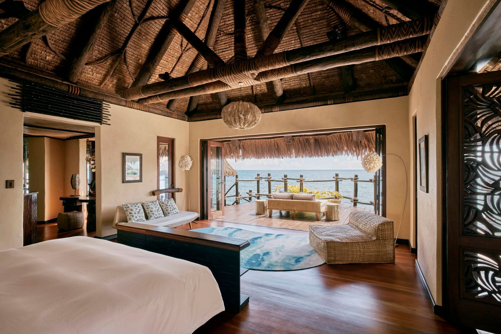 Schlafbereich einer Villa mit geöffneter Front zur Holzterrasse und Blick auf das Meer.