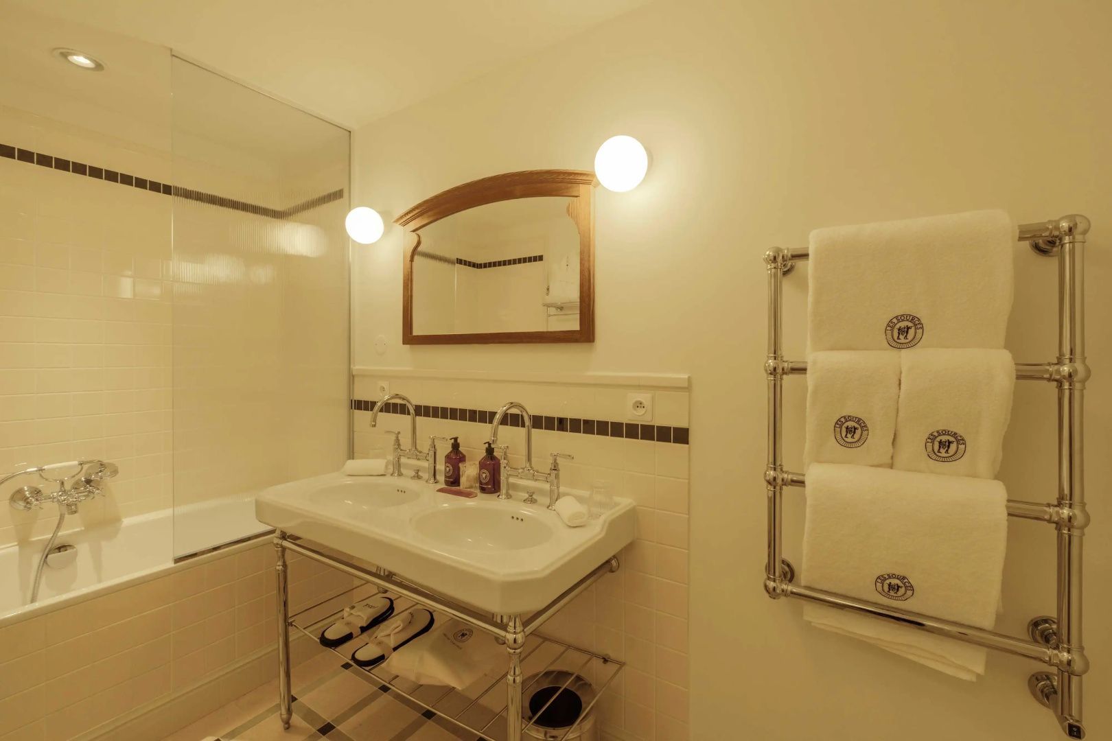 Badezimmer mit Doppelwaschbecken auf Metallgestell und Handtuchhalter mit weißen Tüchern.