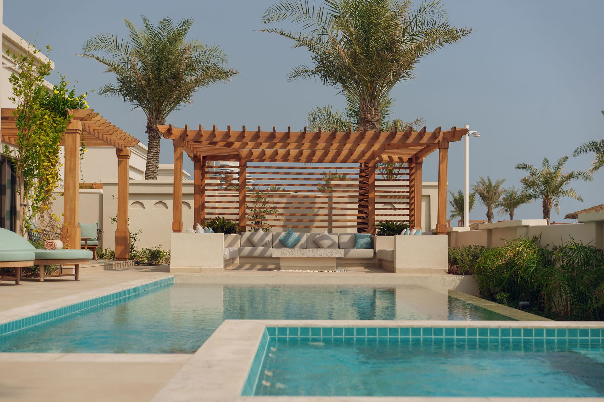 Privatpool mit Liegebereichen und Palmen im Hintergrund