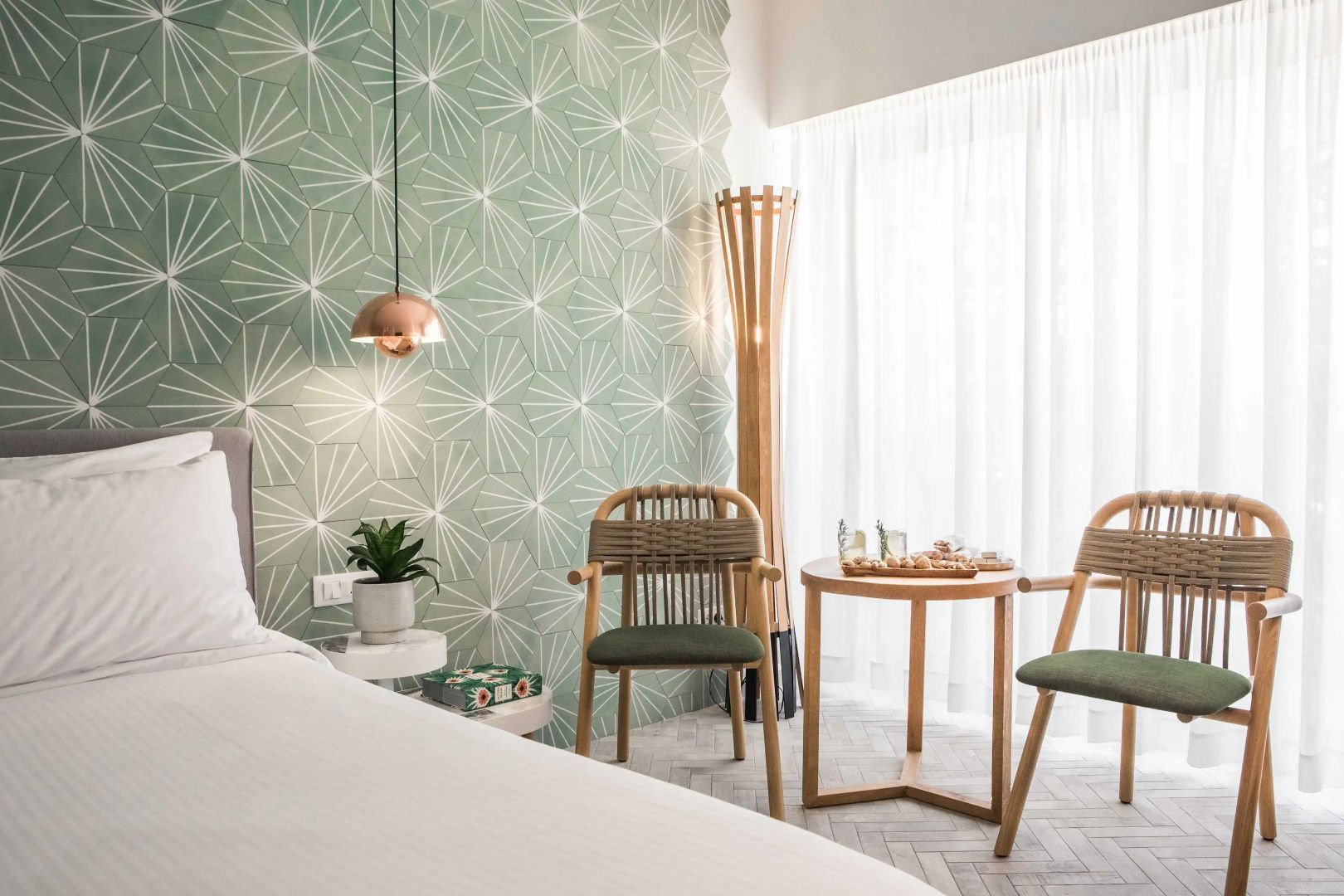 Sitzbereich im Hotelzimmer mit zwei Holzstühlen und einer grünen Mustertapete.