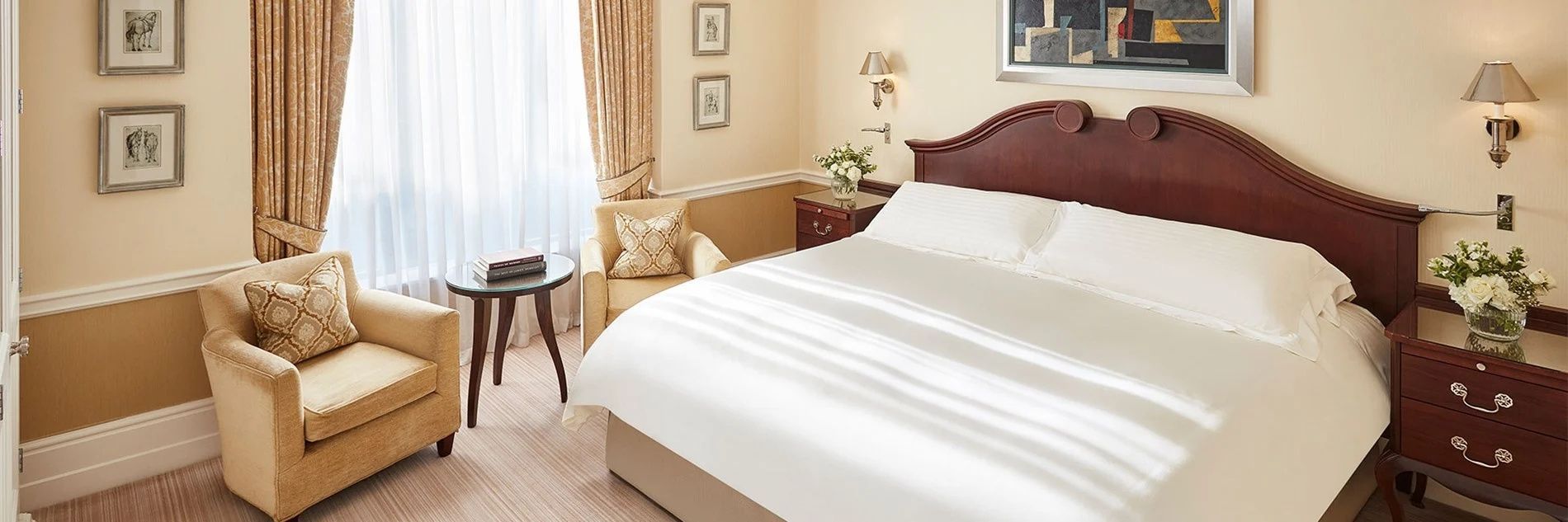 Doppelbett mit weißer Bettwäsche neben einem beigen Sessel im Hotelzimmer