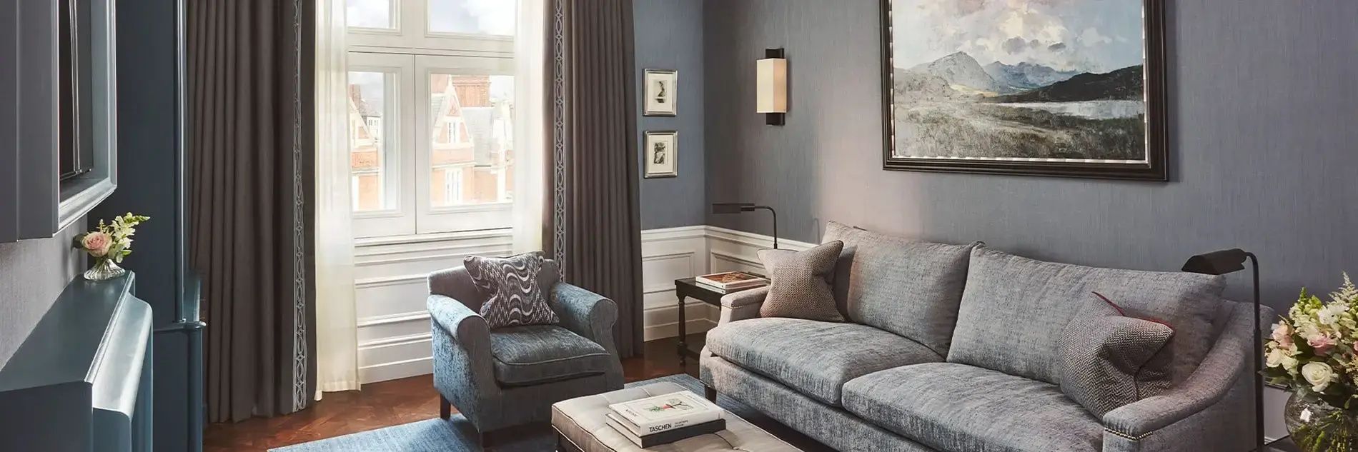 Graues Sofa und blauer Sessel mit Beistelltisch in einem Zimmer mit blauen Wänden.