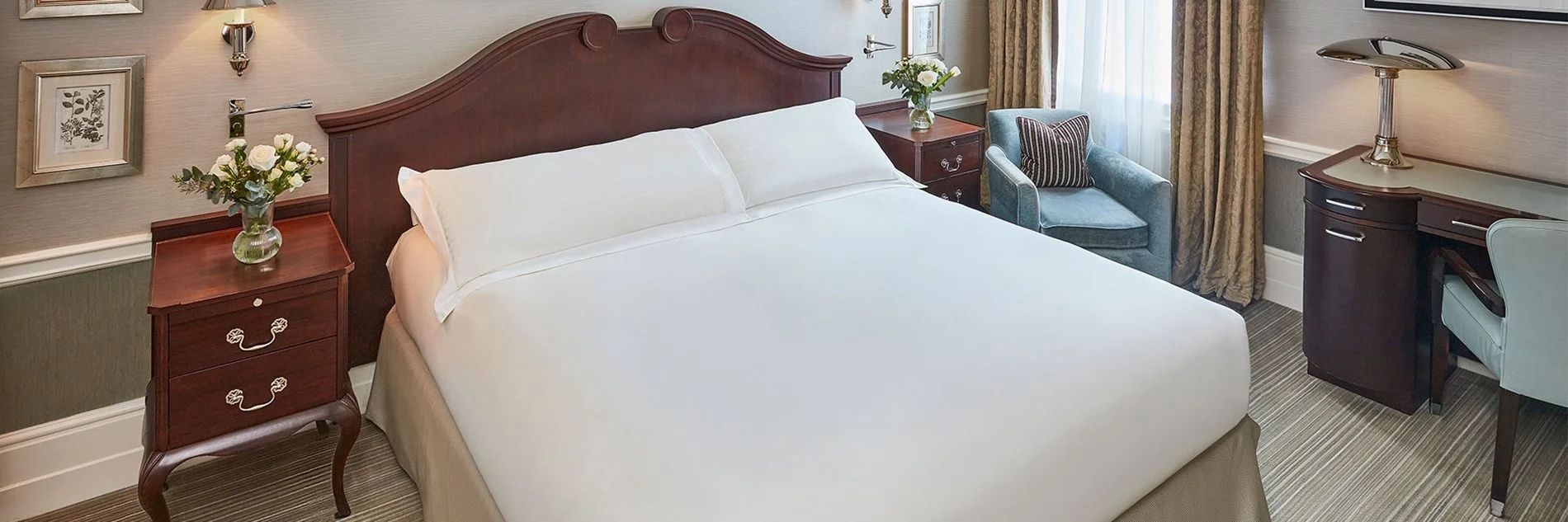 Bett mit zwei weißen Kissen und dunklem Holzrahmen im Hotelzimmer