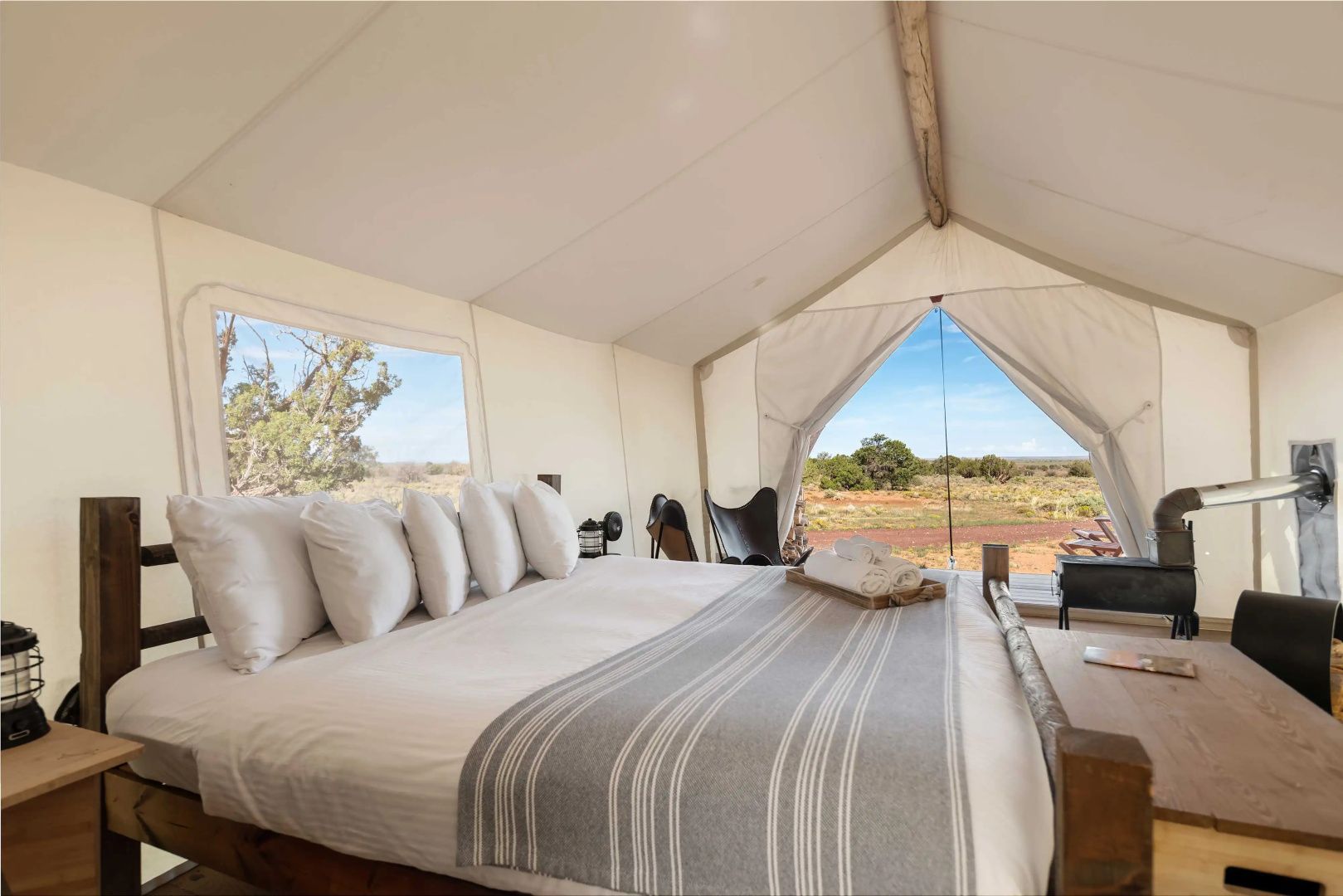Glamping-Zelt mit einem großen Doppelbett und Blick durch das offene Zelt nach draußen.