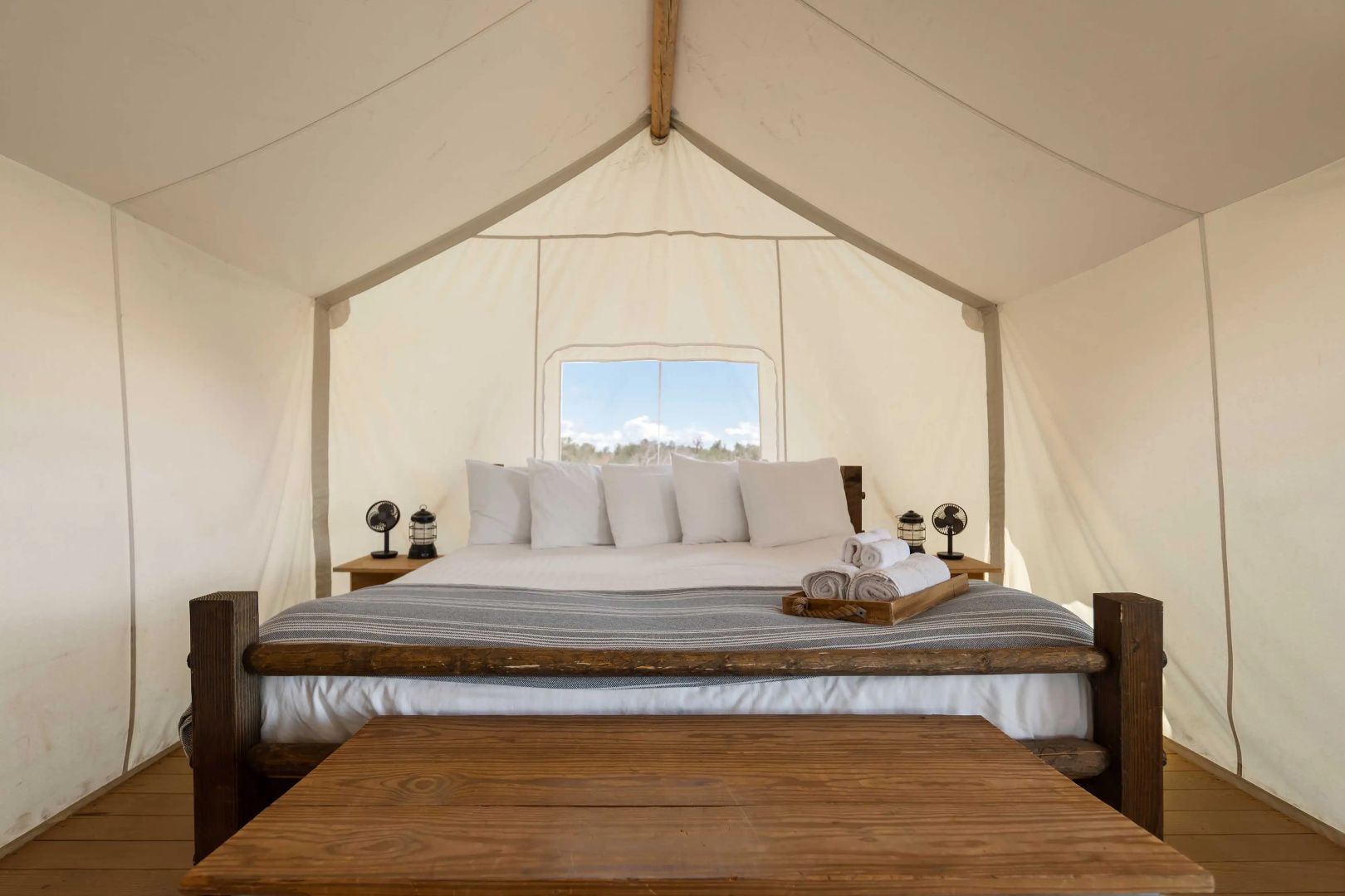 Großes Doppelbett aus Holz mit weißen Kissen in einem Safari-Zelt.