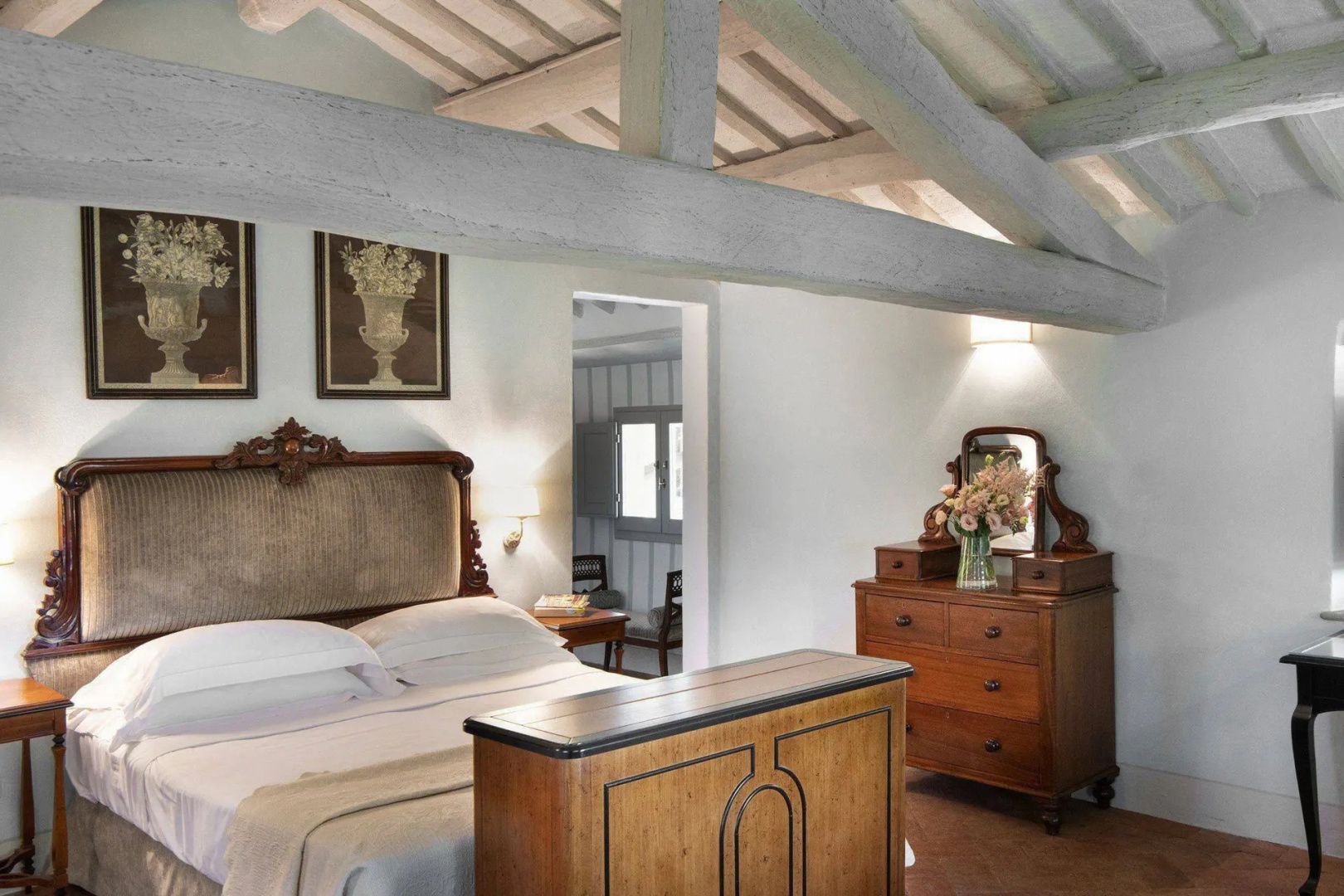 Schlafzimmer mit rustikaler Holzbalkendecke, einem Doppelbett und Kommode aus Holz.