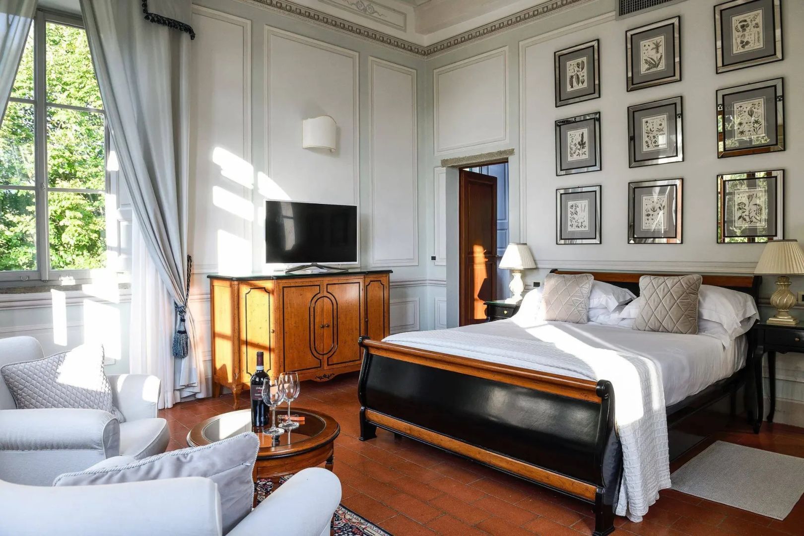 Schlafzimmer mit großem Holzdoppelbett, Kommode mit Fernseher und Wandbildern.