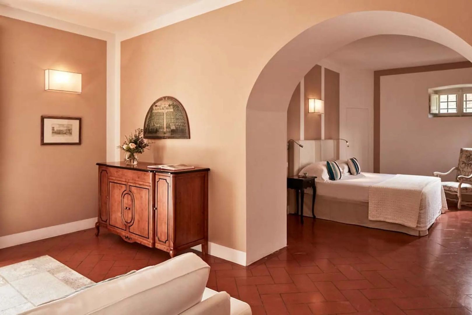 Wohnbereich einer Suite mit Holzkommode und Durchgang zum Schlafzimmer.