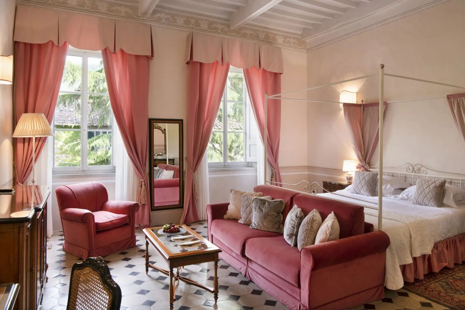 Wohnbereich einer Suite mit rosa Sofa, passendem Sessel und rosa Vorhängen am Fenster.